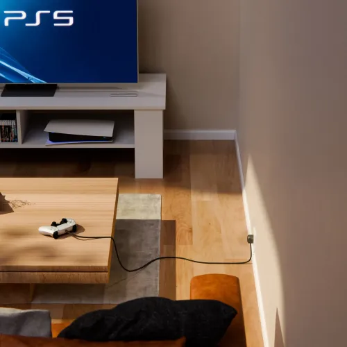 Twelve South PowerCord, ein 3 m langes Ladekabel in einem Gaming-Setup im Wohnzimmer, das von einem Controller zu einer Wandsteckdose führt.