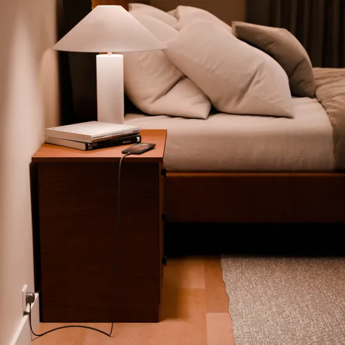 Twelve South PowerCord-opladningsopsætning ved sengen med sort flettet USB-C-kabel tilsluttet en smartphone.