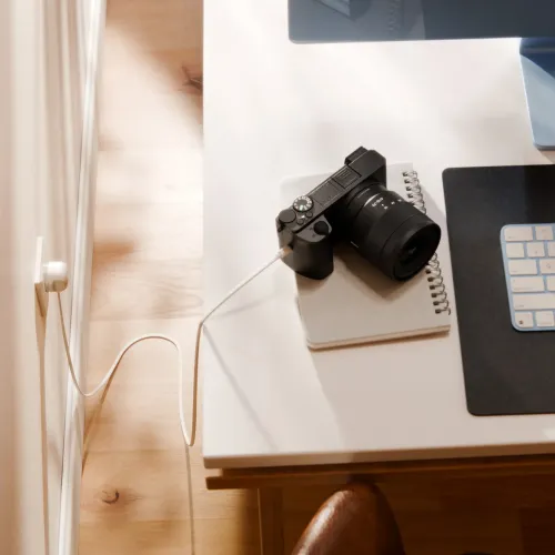 Twelve South PowerCord balts USB-C lādētāja kabelis, iesprausts sienas kontaktligzdā blakus rakstāmgalda aprīkojumam