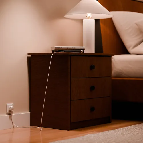 Twelve South PowerCord weißes USB-C-Ladekabel neben einem Nachttisch in einer warmen Schlafzimmerumgebung