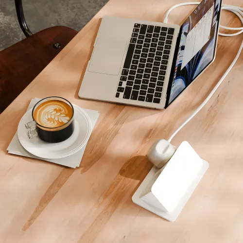 Twelve South PowerCord 3 m baltas USB-C įkroviklis, prijungtas prie nešiojamojo kompiuterio ant šviesaus medinio stalo